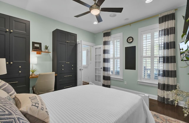 bedroom featuring multiple windows, ceiling fan, and dark hardwood / wood-style flooring