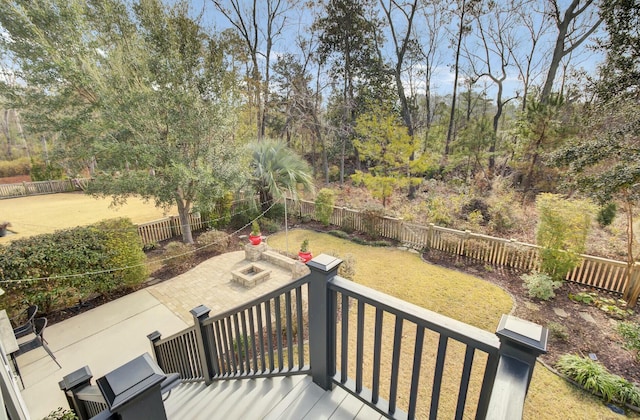 wooden terrace featuring a yard, a fire pit, and a patio