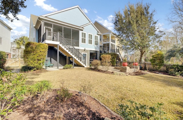 rear view of property featuring a yard, a sunroom, and ceiling fan