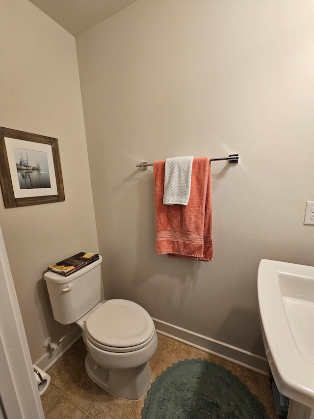 bathroom featuring baseboards, a sink, toilet, and tile patterned floors