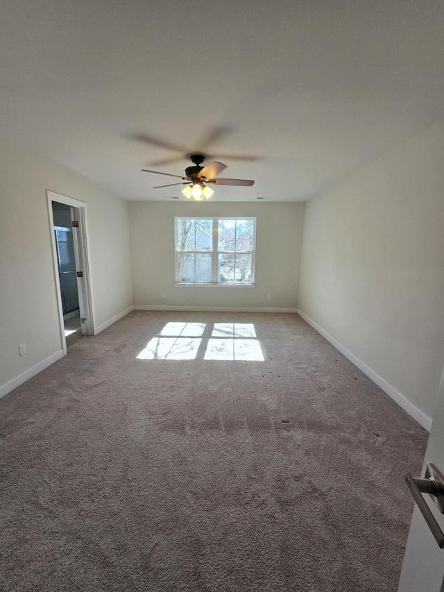 carpeted spare room with a ceiling fan and baseboards