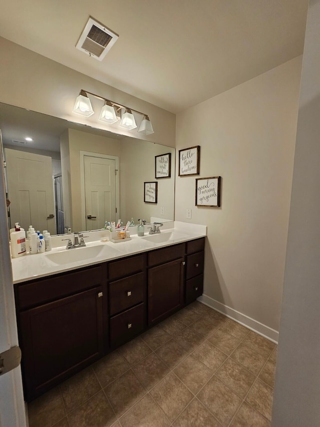 bathroom featuring double vanity, a sink, visible vents, and baseboards