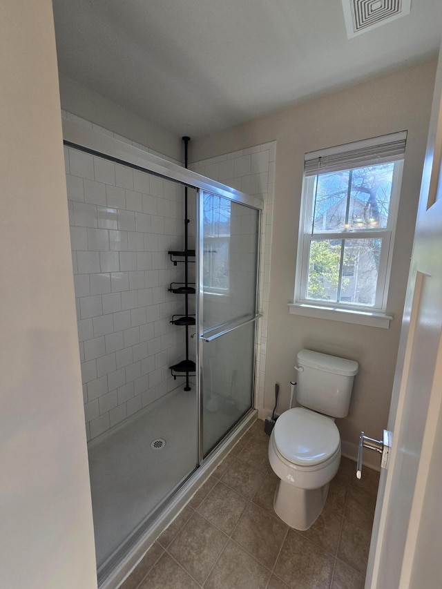 bathroom featuring toilet, a stall shower, visible vents, and tile patterned floors