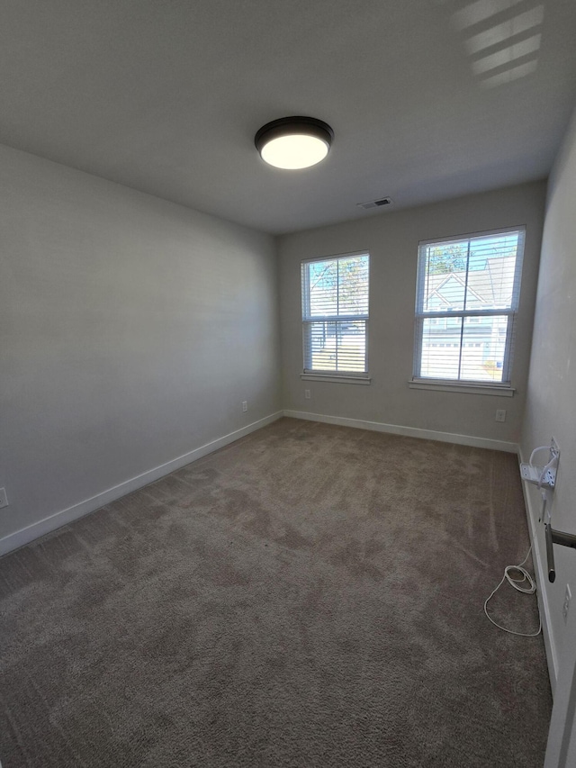 unfurnished room featuring carpet, visible vents, and baseboards