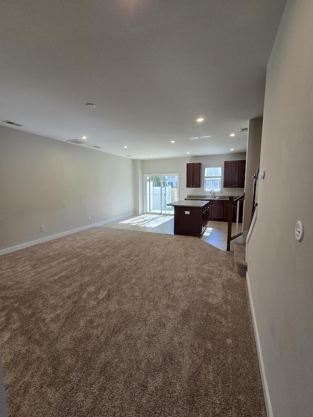 unfurnished living room featuring recessed lighting, light colored carpet, visible vents, and baseboards