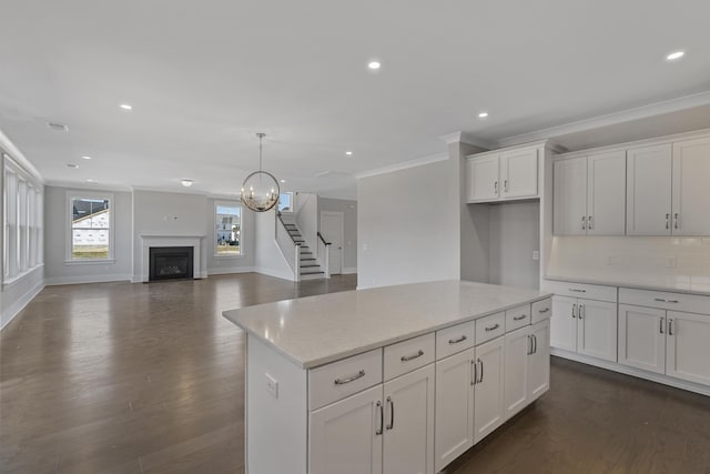 kitchen with dark wood-type flooring, light stone countertops, a kitchen island, and white cabinets