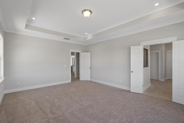 unfurnished bedroom featuring crown molding, a raised ceiling, and light carpet