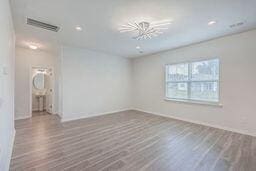 empty room featuring wood-type flooring and a chandelier