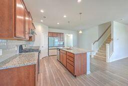 kitchen featuring an island with sink, light wood-type flooring, light stone counters, and backsplash