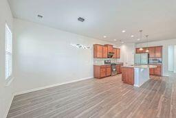 kitchen featuring stainless steel range oven, hanging light fixtures, wood-type flooring, a center island, and white refrigerator