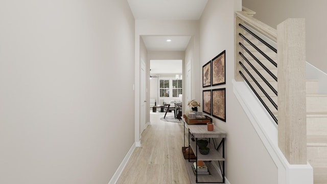 hall with stairway, light wood-style flooring, and baseboards