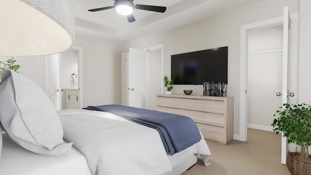 bedroom with baseboards, connected bathroom, light colored carpet, ceiling fan, and a tray ceiling