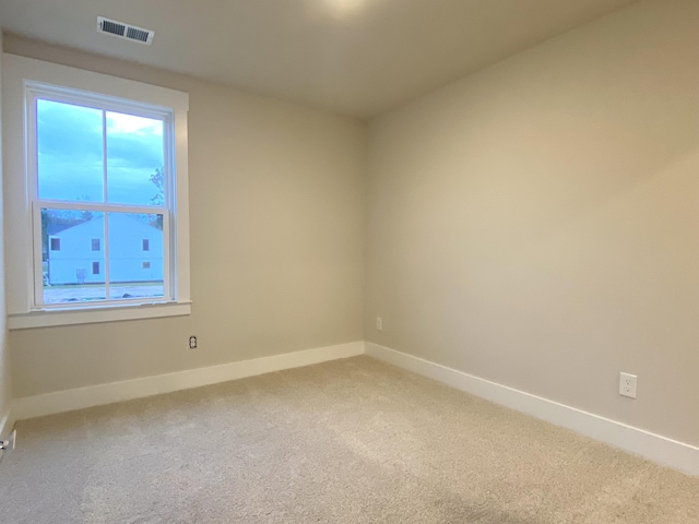 unfurnished room with baseboards, visible vents, and light colored carpet