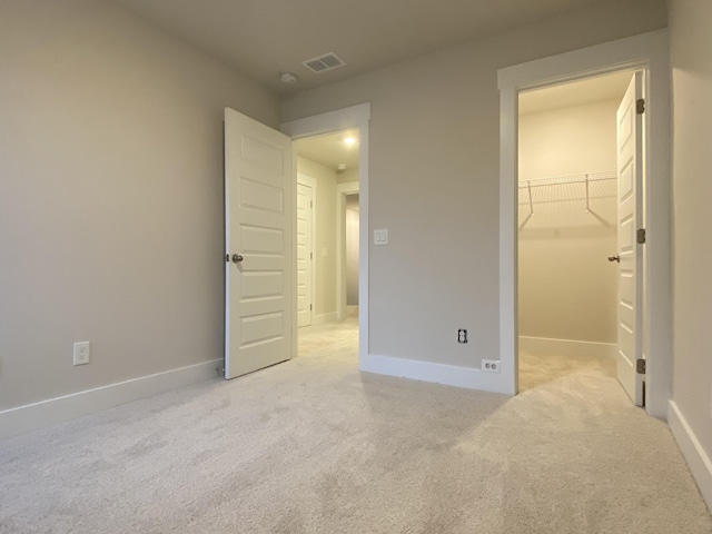 unfurnished bedroom featuring baseboards, visible vents, and light colored carpet