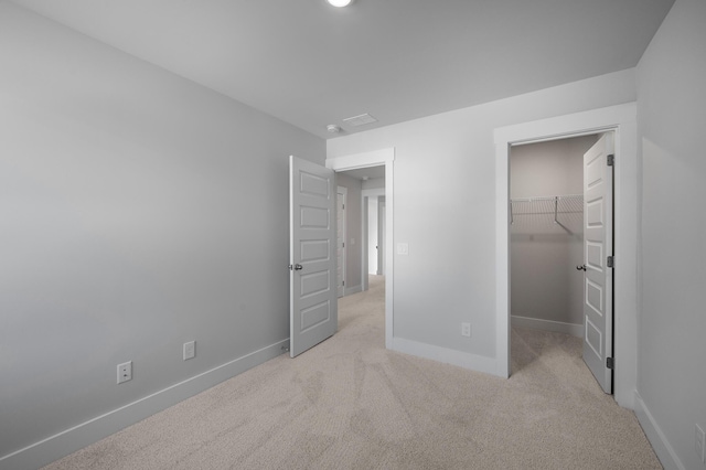 unfurnished bedroom featuring a closet, visible vents, a spacious closet, carpet flooring, and baseboards