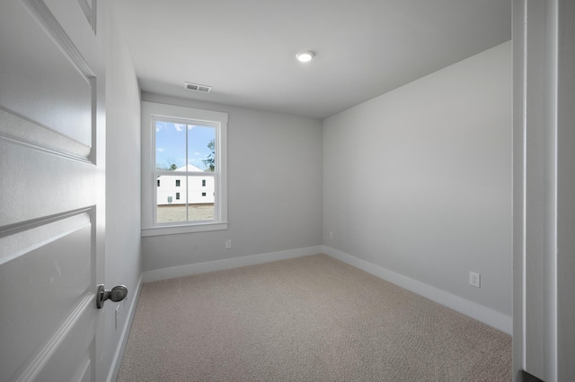 carpeted spare room with visible vents and baseboards