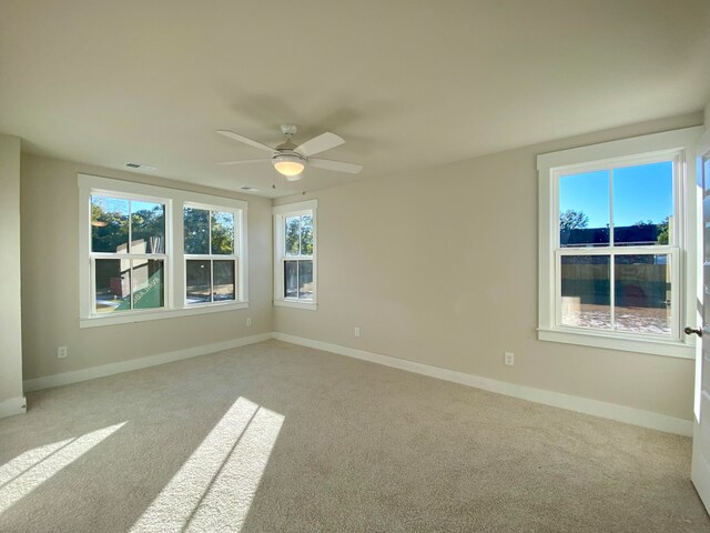 carpeted empty room featuring a ceiling fan, visible vents, and baseboards