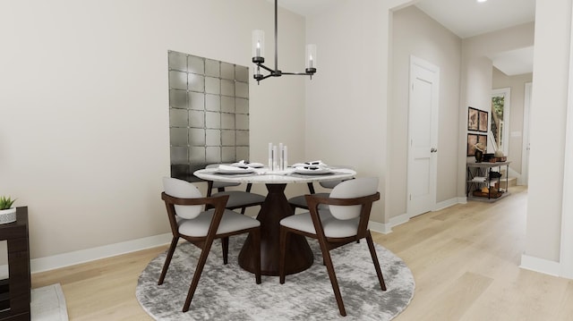 dining room with a chandelier, baseboards, and light wood finished floors