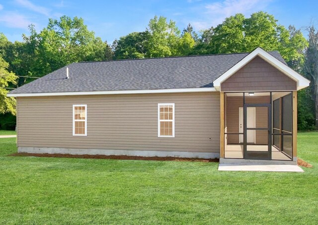 222 New Iris Ln, Ridgeville, SC 29472 - back of property featuring a shingled roof, a sunroom, and a lawn