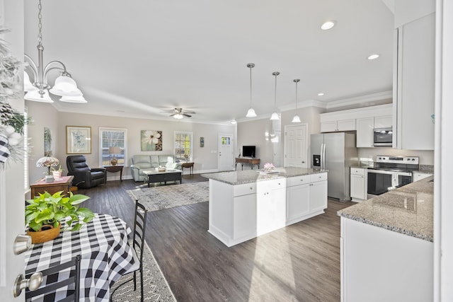 kitchen with light stone countertops, white cabinets, a kitchen island, decorative light fixtures, and stainless steel appliances