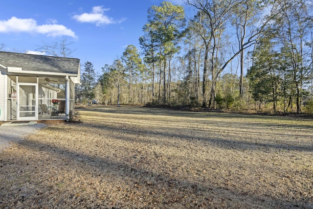 view of yard featuring ceiling fan and a sunroom