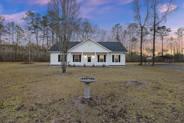 view of front of house with a yard, a porch, and a carport