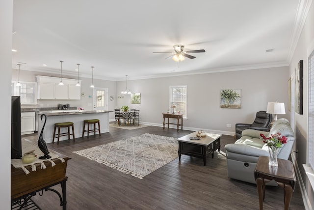 living room featuring dark hardwood / wood-style flooring, crown molding, and ceiling fan with notable chandelier