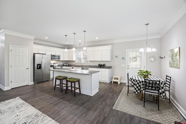 kitchen with white cabinetry, a breakfast bar area, appliances with stainless steel finishes, hanging light fixtures, and a kitchen island