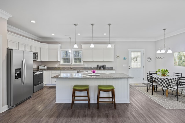 kitchen featuring white cabinets, appliances with stainless steel finishes, a kitchen island, decorative light fixtures, and sink