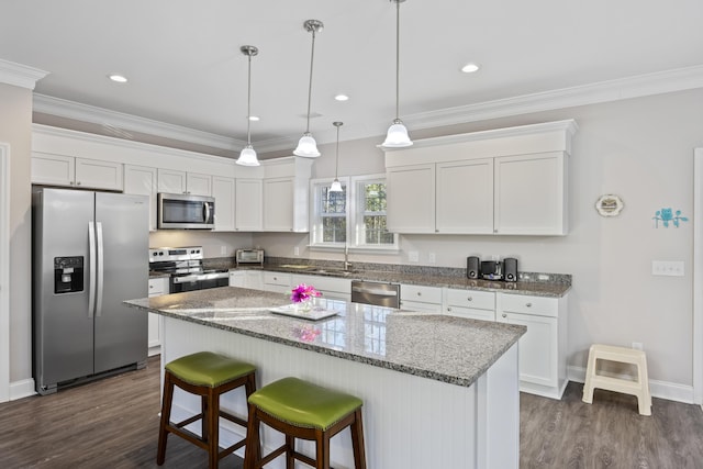 kitchen with white cabinetry, appliances with stainless steel finishes, a center island, and dark stone counters