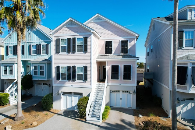 coastal home featuring stairs, an attached garage, and driveway