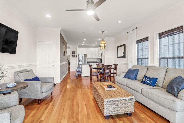 living room with ceiling fan, crown molding, and light wood finished floors