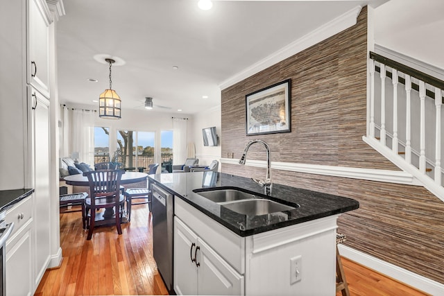 kitchen with light wood-style flooring, an island with sink, a sink, white cabinetry, and dishwasher