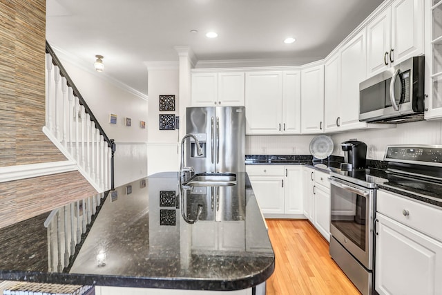 kitchen featuring light wood finished floors, white cabinetry, stainless steel appliances, and crown molding