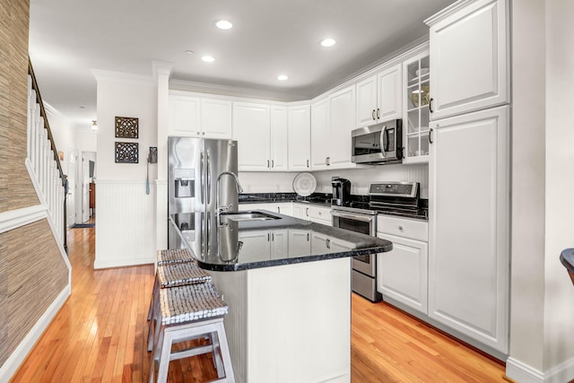 kitchen featuring a wainscoted wall, white cabinetry, stainless steel appliances, and a sink