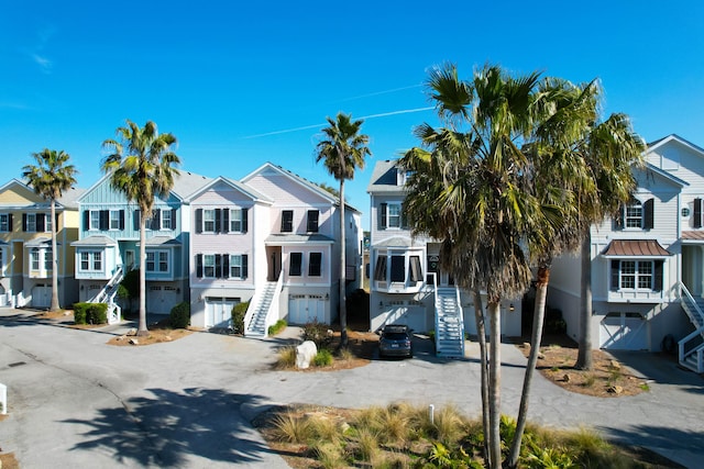 view of property with stairway, a residential view, concrete driveway, and a standing seam roof