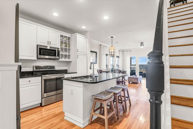 kitchen featuring dark countertops, a kitchen breakfast bar, white cabinets, stainless steel appliances, and a sink