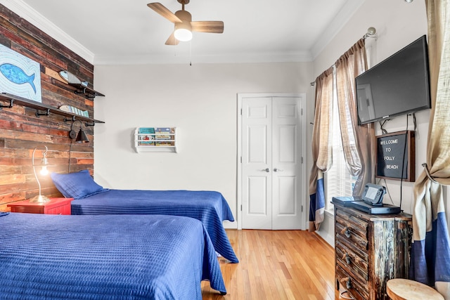 bedroom featuring a ceiling fan, wood finished floors, a closet, and ornamental molding