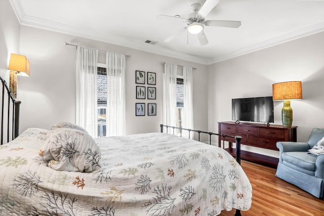 bedroom featuring visible vents, multiple windows, wood finished floors, and ornamental molding