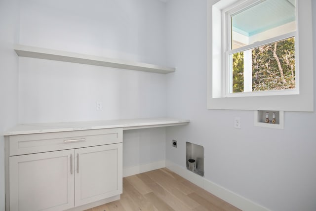 clothes washing area featuring hookup for a washing machine, electric dryer hookup, light hardwood / wood-style flooring, and cabinets