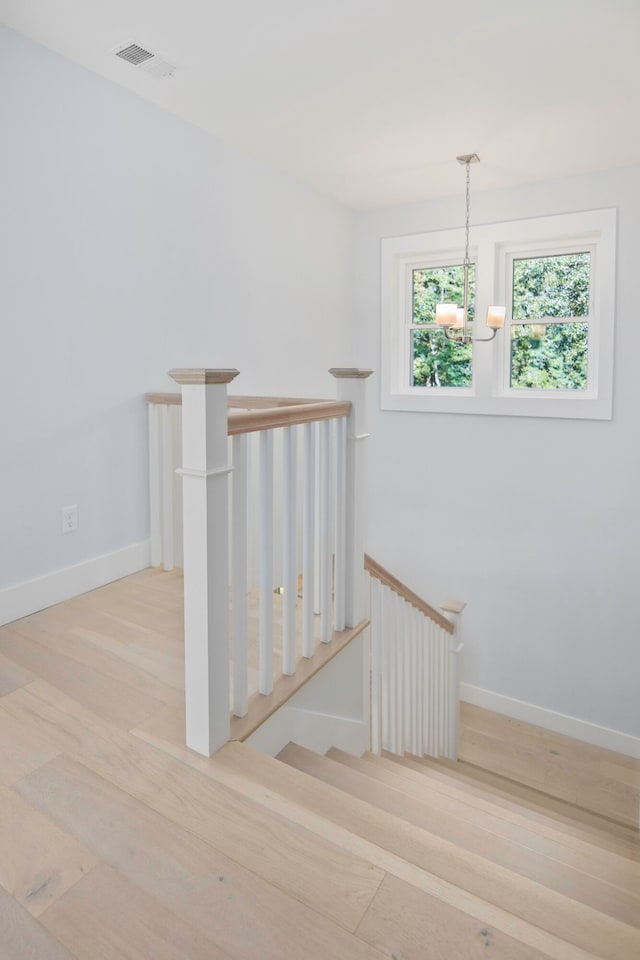 stairway featuring wood-type flooring and a chandelier