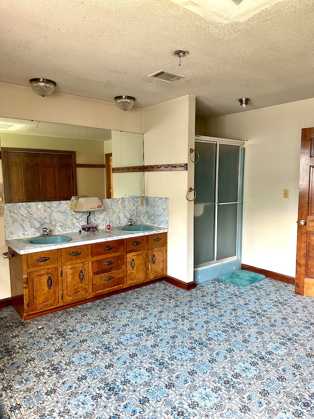 kitchen featuring tile patterned floors, sink, a textured ceiling, and backsplash