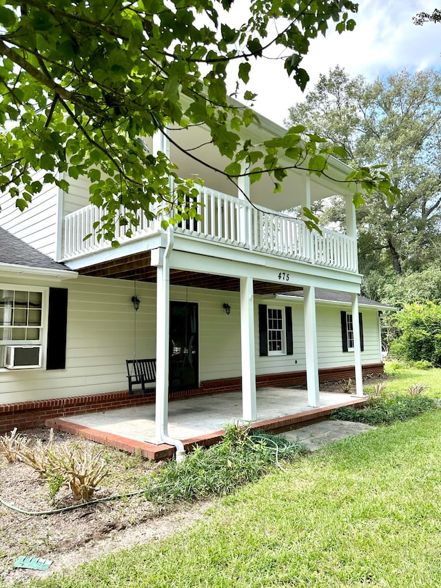 rear view of house with a lawn and a balcony