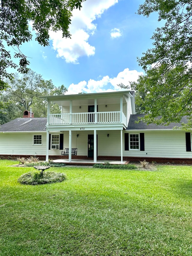 rear view of house featuring a yard and a balcony