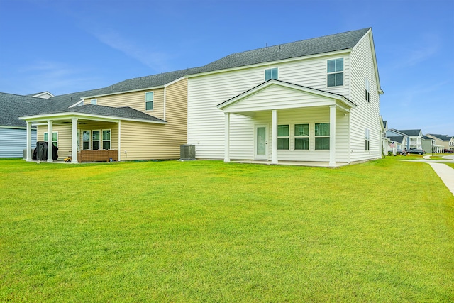 back of property featuring central AC and a lawn