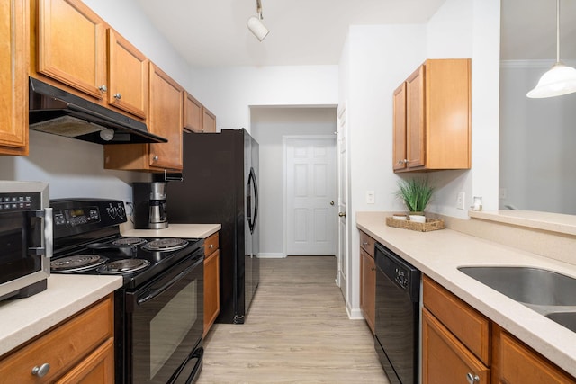 kitchen with light wood-type flooring, light countertops, under cabinet range hood, and black appliances