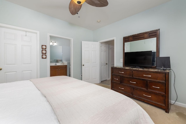 bedroom with light carpet, baseboards, a ceiling fan, ensuite bath, and a sink