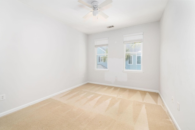 unfurnished room with baseboards, ceiling fan, visible vents, and light colored carpet