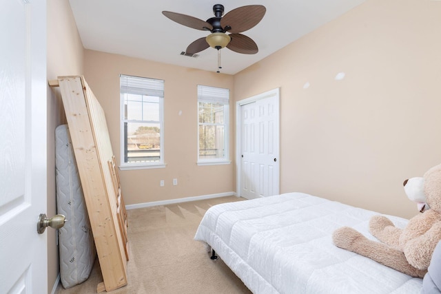 bedroom with a closet, visible vents, a ceiling fan, light carpet, and baseboards