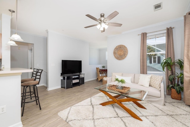 living area with ceiling fan, visible vents, baseboards, light wood-style floors, and crown molding